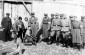 At the main gate of the Kremenets ghetto, a Jewish boy polishes the boots of Jewish policemen as German policemen look on. ©Photo archive, taken from yadvashem.org