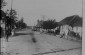 View of a cobblestone street lined with low buildings: passersby walk on sidewalks, (center) a young man on a bicycle, and (back) a church.1920s-1930s © From the Archives of the YIVO Institute for Jewish Research